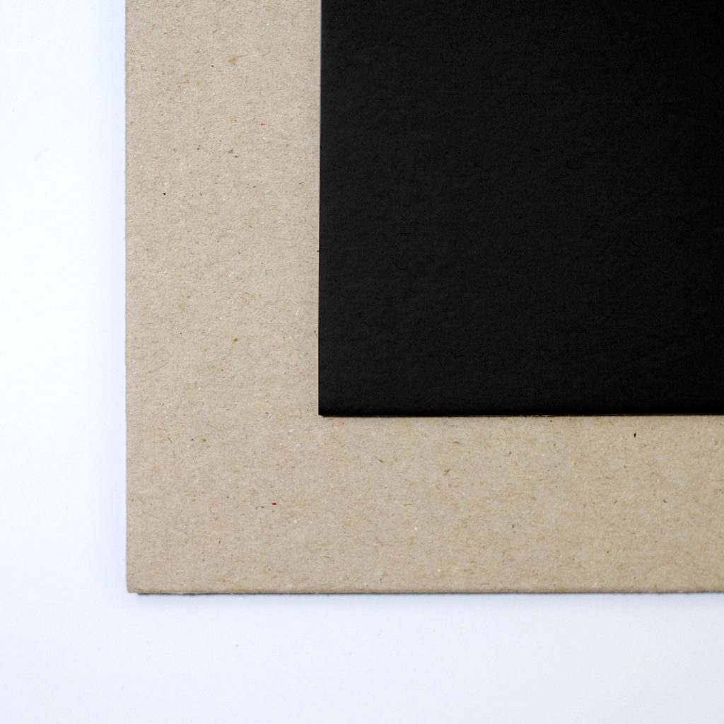 Close up of texture of a solid one-sided grey, one-sided black paperboard.